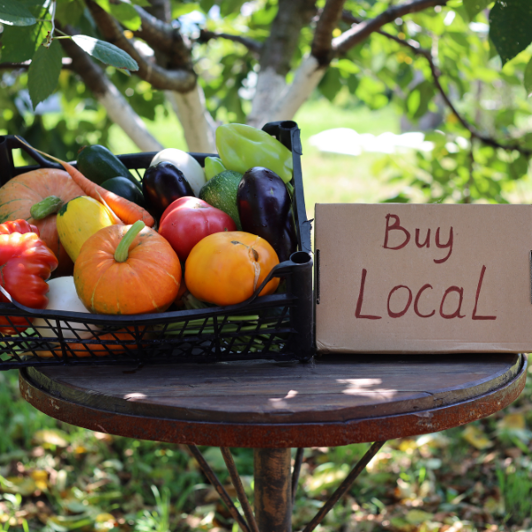 a basket of fruit sitting on an outdoor table next to a sign that says buy local